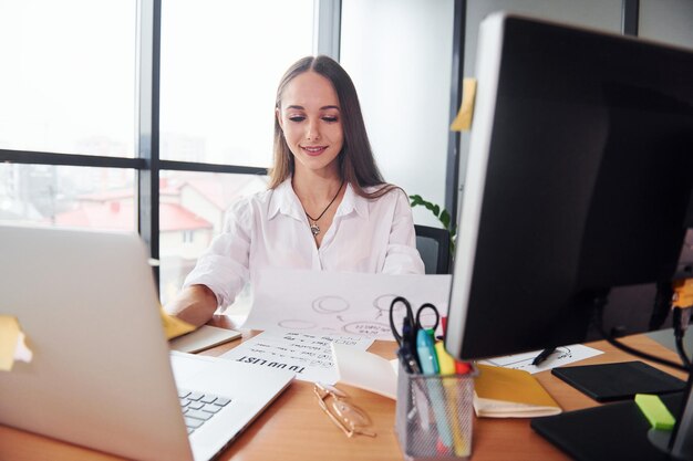 Busy day Young adult woman in formal clothes is indoors in the office