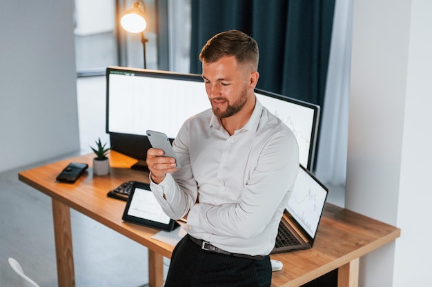 Busy day Young businessman in formal clothes is in office with multiple screens