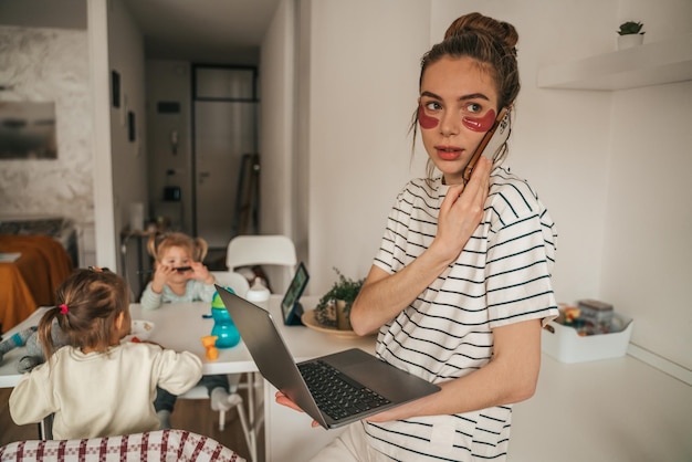 Foto mamma freelance occupata e bambini che giocano in cucina