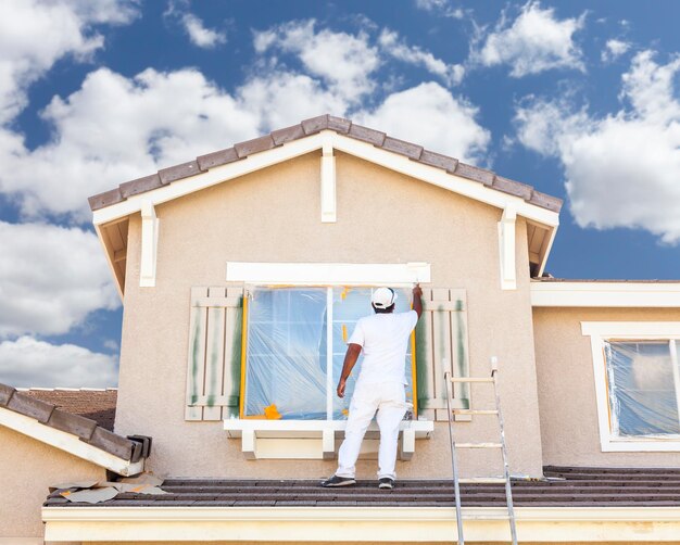 Photo busy house painter painting the trim and shutters of a home