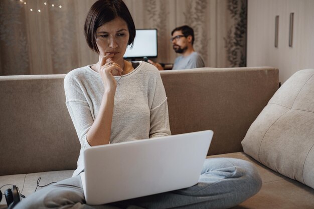 Busy man and woman studying hard with laptop on deadline in living room at home