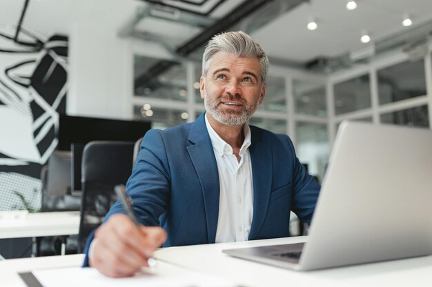 Busy Mature businessman working with documents while sitting in modern coworking