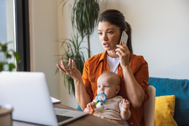 바쁜 어머니는 딸을 돌보고 집에서 일하면서 전화 통화를 합니다.