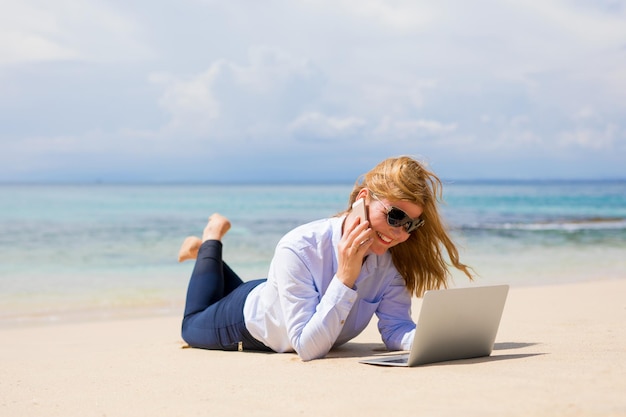 Busy woman enjoying working from the beach