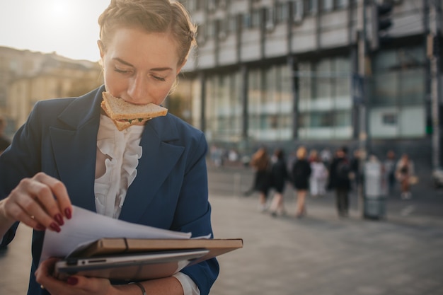 Busy woman is in a hurry, she does not have time, she is going to eat snack on the go. worker eating, drinking coffee, talking on the phone, at the same time. businesswoman doing multiple tasks.