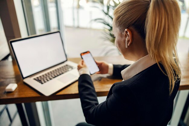 A busy woman is using technologies phone and laptop at coffee shop and working remotely