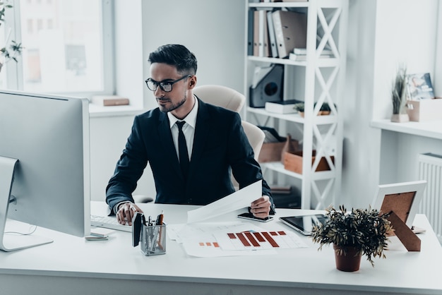 Busy at work. Handsome young man in full suit working with documents 