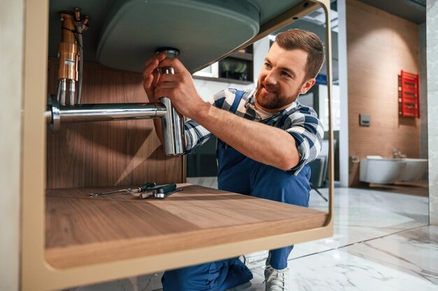 Photo busy worker in blue uniform is in the bathroom