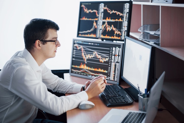 Busy working day. Close-up of young businessman looking at monitor while sitting at the desk in creative office