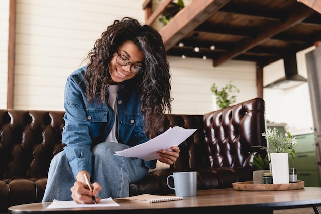 Busy young african businesswoman working with documents at home
african woman managing