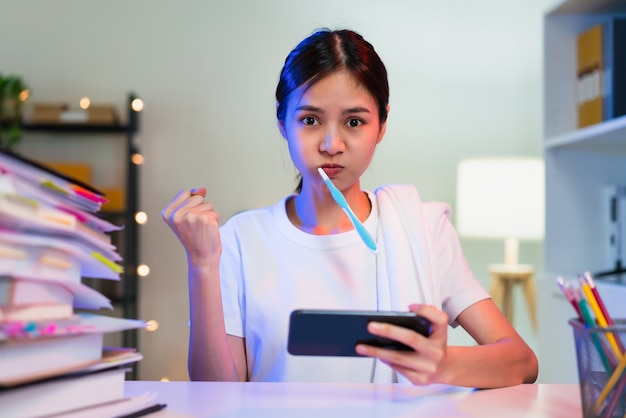 Busy young asian woman brushing teeth and hand playing online game on smartphone.