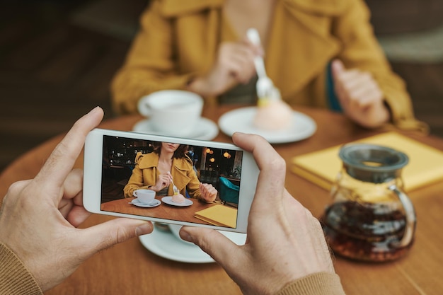 モダンなカフェのテーブルに座って、プロジェクトについて話している間コーヒーを飲む忙しい若いひげを生やした男