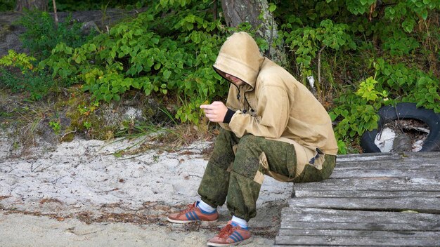 Busy young environmentalist is working on the phone in the woods young man sitting in the woods with