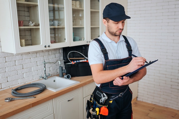 Busy young handyman stands in kitchen