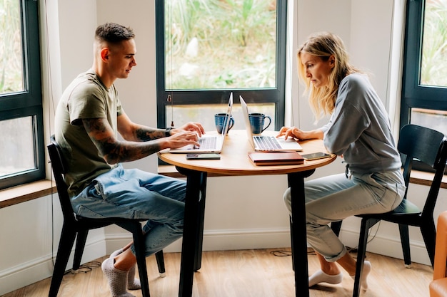 Photo busy young man and woman work online on laptops at home at the table in the living room