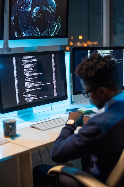 Busy young programmer looking at wristwatch while working late