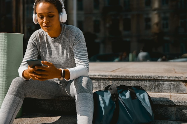 busy young woman using mobile phone after workout outdoors active lifestyle sport concept