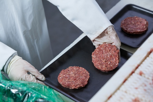 Foto macellaio organizzando tortino di hamburger sul vassoio