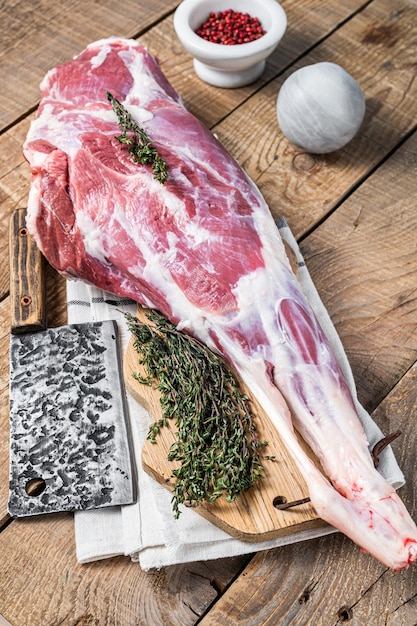 Butcher board with Raw lamb mutton leg with herbs Wooden background Top view