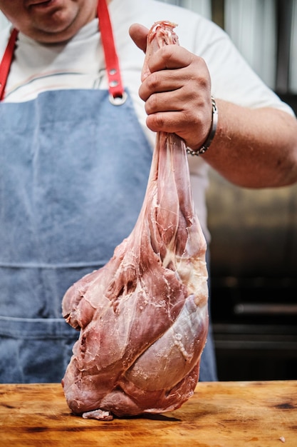 고기를 굽기 위해 양고기 다리를 정육하고 있는 정육점 Pitmaster는 훈제 고기를 준비합니다.