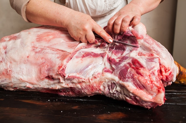 Butcher carving pork carcass in market