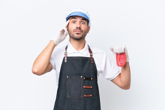 Butcher caucasian man wearing an apron and serving fresh cut meat over isolated white background thinking an idea