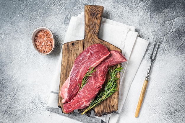 Butcher choise Bavette raw beef meat steak or flank flap on a wooden board with herbs White background Top view