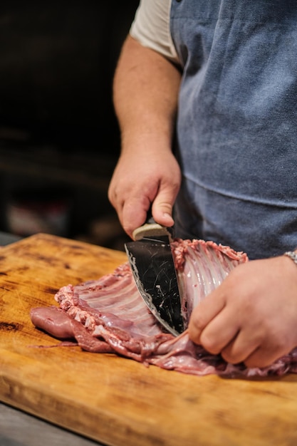 Foto il macellaio pulisce le costine di agnello preparazione della carne per l'affumicatura o il barbecue