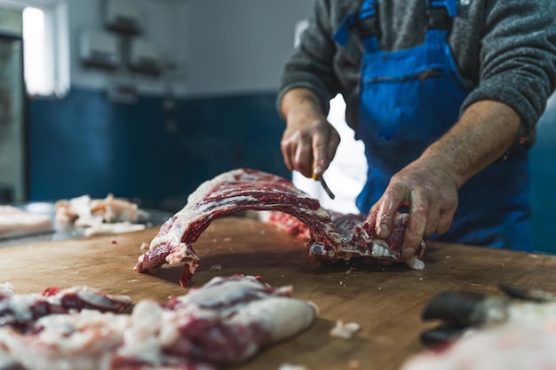 Butcher cut raw meat of a pig with a knife at table in the slaughterhouse