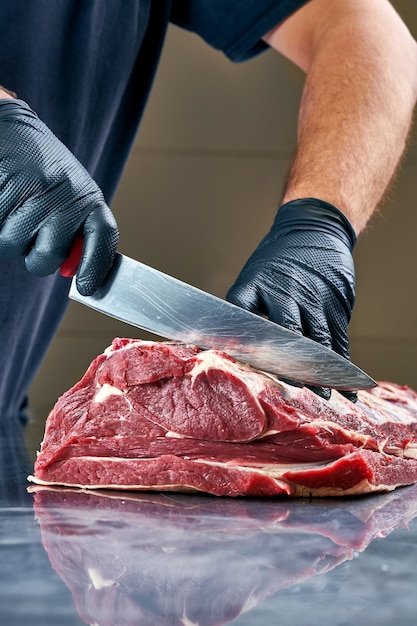 Photo butcher cuts a fresh piece of beef on the table