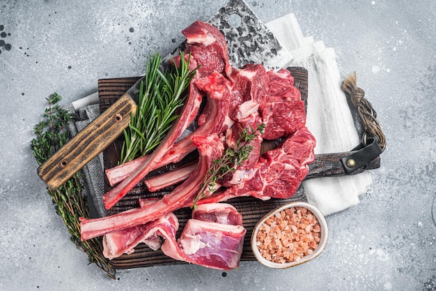 Butcher cutting board with butchered Raw Lamb chop steak or mutton cutlet Gray background Top view