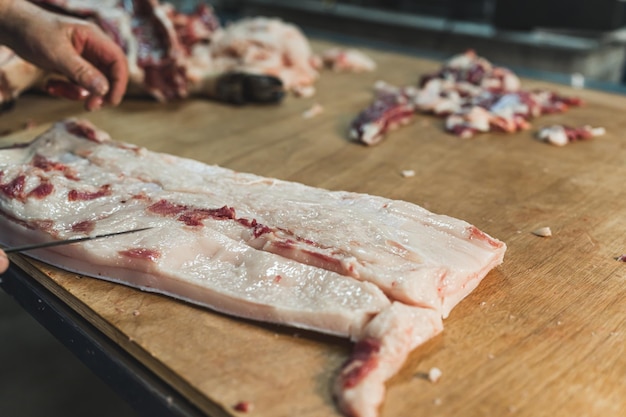 A butcher cutting pigskin on the wooden table preparing pork