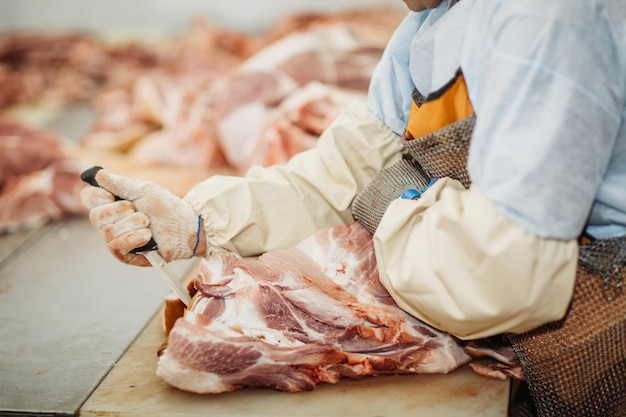 Мясник режет свинину в мясной промышленности
