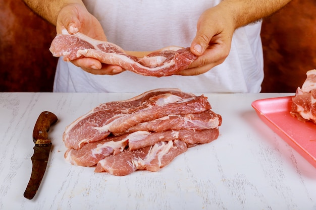 肉屋の新鮮な生の肉とポークチョップの豚肉を切る