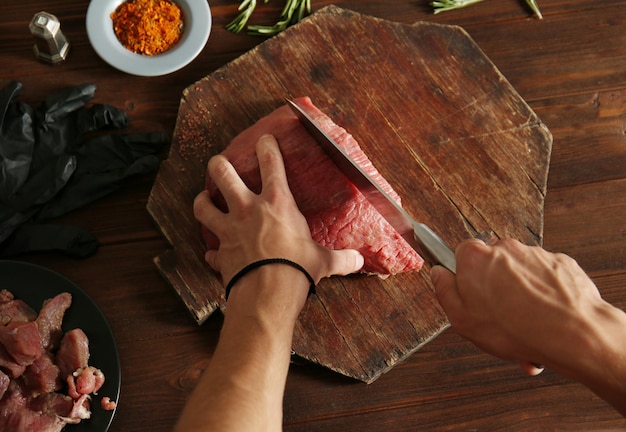 Butcher cutting pork meat on kitchen