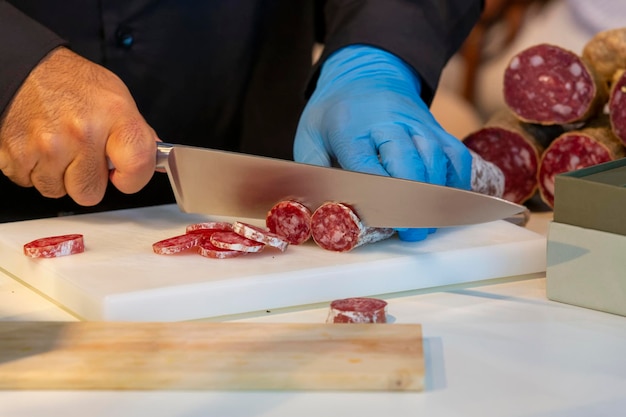 Foto il macellaio taglia fette di salsiccia con un grosso coltello