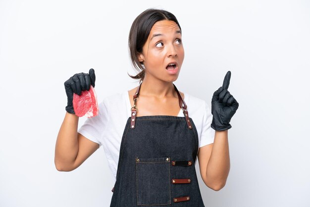 butcher hispanic woman wearing an apron and serving fresh cut meat isolated on white background thinking an idea pointing the finger up