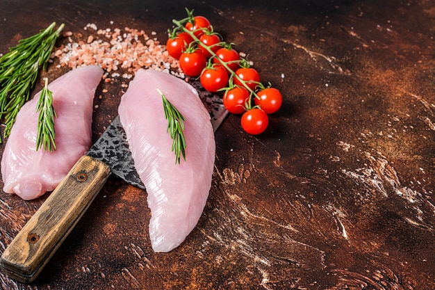 Butcher Raw Turkey steaks, Breasts fillet on a meat cleaver. Dark background. Top view. Copy space.