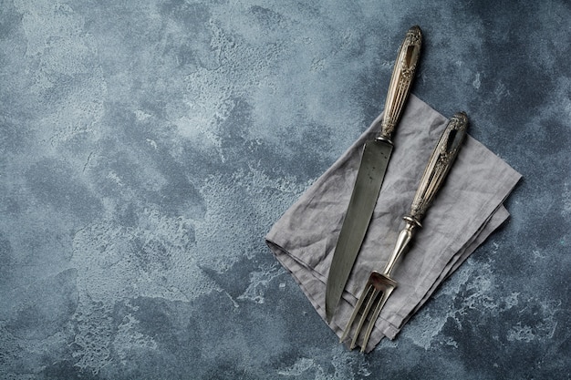 Butcher. Vintage meat knife and fork over a dark gray old stone table