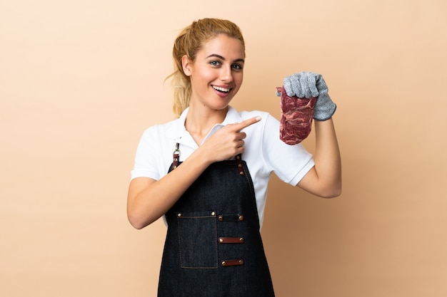 Женщина мясника в фартуке и подача свежего нарезанного мяса на изолированный указательный палец в сторону