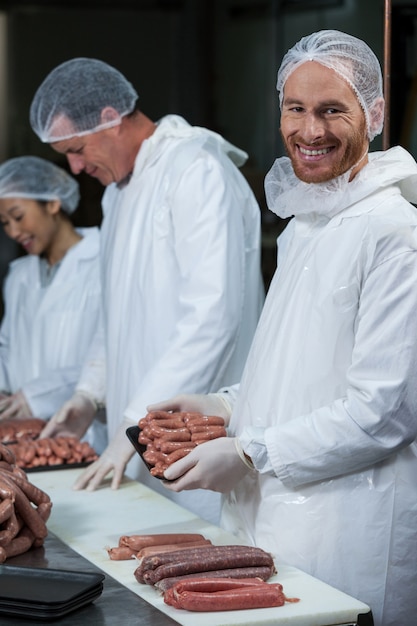 Butchers packing raw sausages