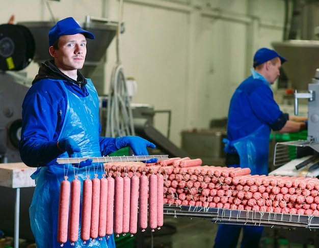 Butchers processing sausages at meat factory.