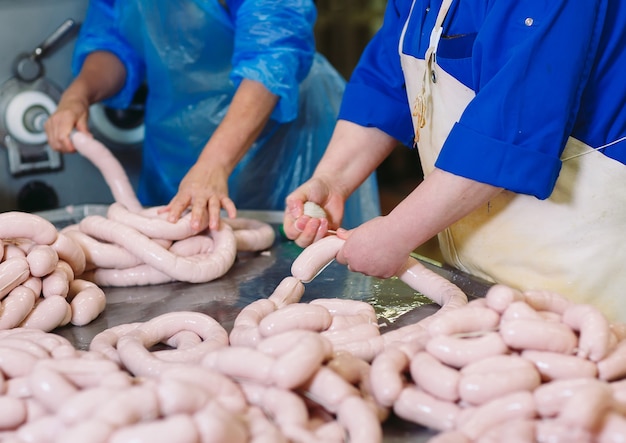 Butchers processing sausages at meat factory.