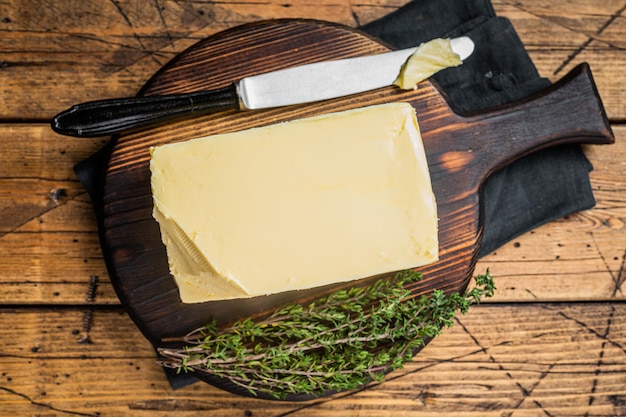 Butter block on wooden board with herbs Wooden background Top view