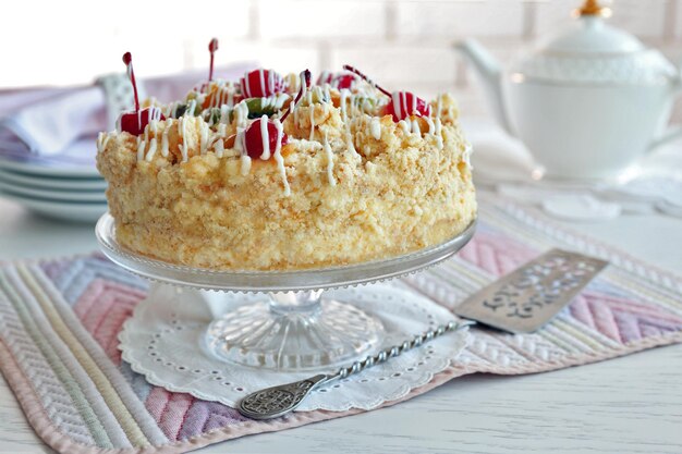 Butter cake with cherries on stand on color wooden background