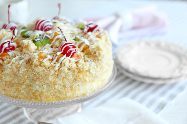 Butter cake with cherries on stand and table setting on light background