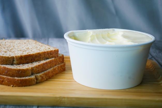 Butter in a container and whole meal bread on chopping board