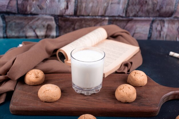 Butter cookies and a glass of milk on a cutting board