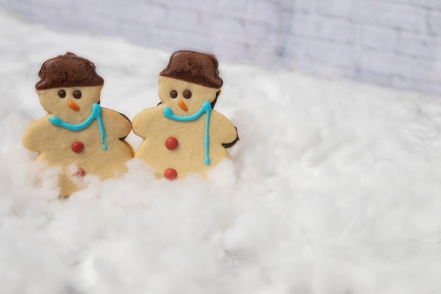 Butter cookies in the shape of a snowman on snow with a white background, Christmas background,