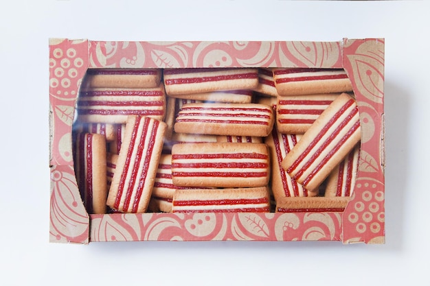 Butter cookies with jam in a carton on white background